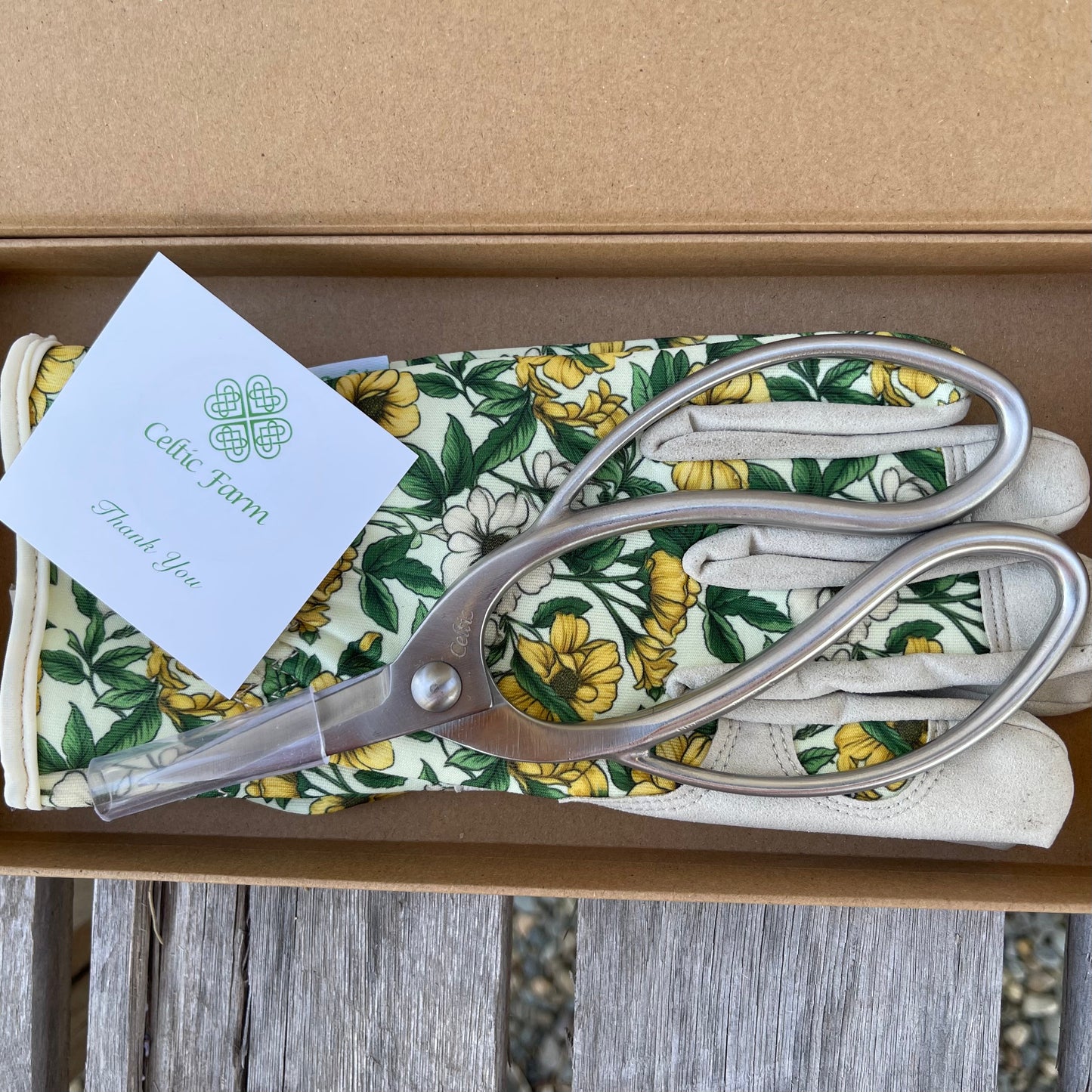 Scissors and floral-patterned shears case with a card on a wooden surface