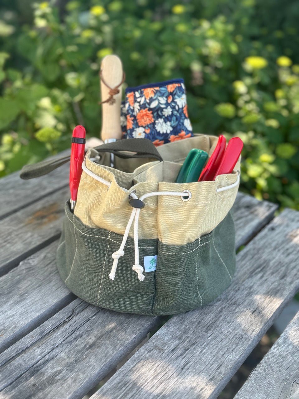 Green fabric tool roll with tools on a wooden surface outdoors