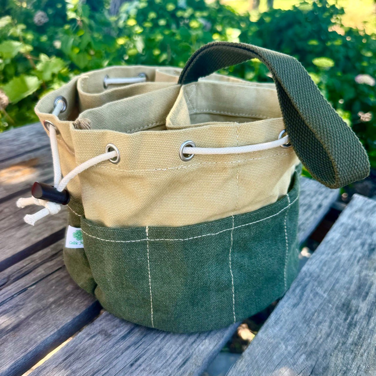 Green and beige fabric bag with handles on a wooden surface