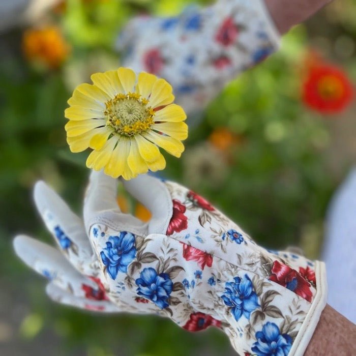 Floral-patterned glove holding a yellow flower with a blurred floral background