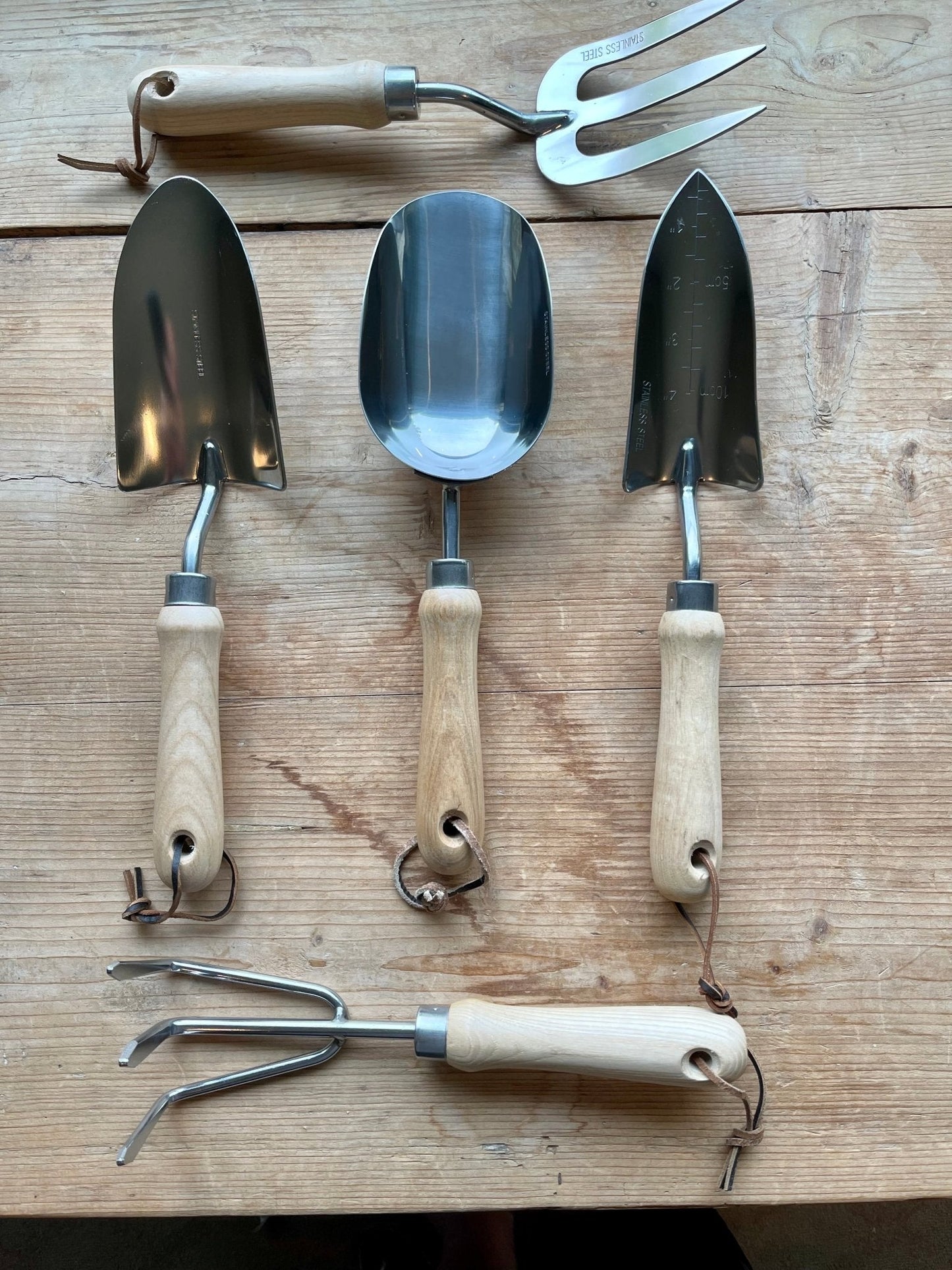 Set of gardening tools with wooden handles on a wooden surface