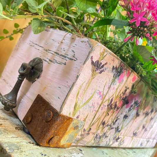 Decorative wooden box with floral design and metal handle on a natural background