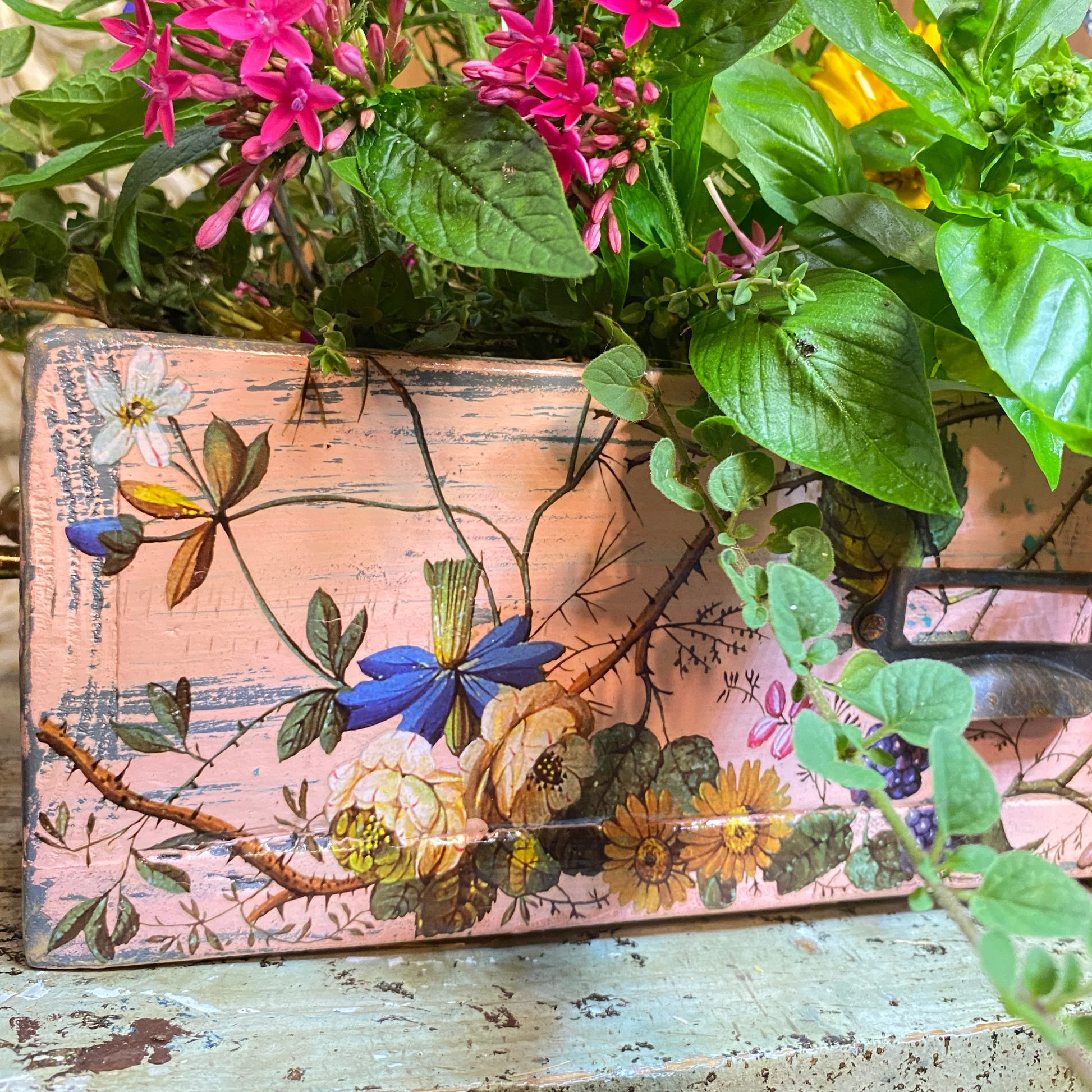 Decorative wooden box with floral design surrounded by greenery