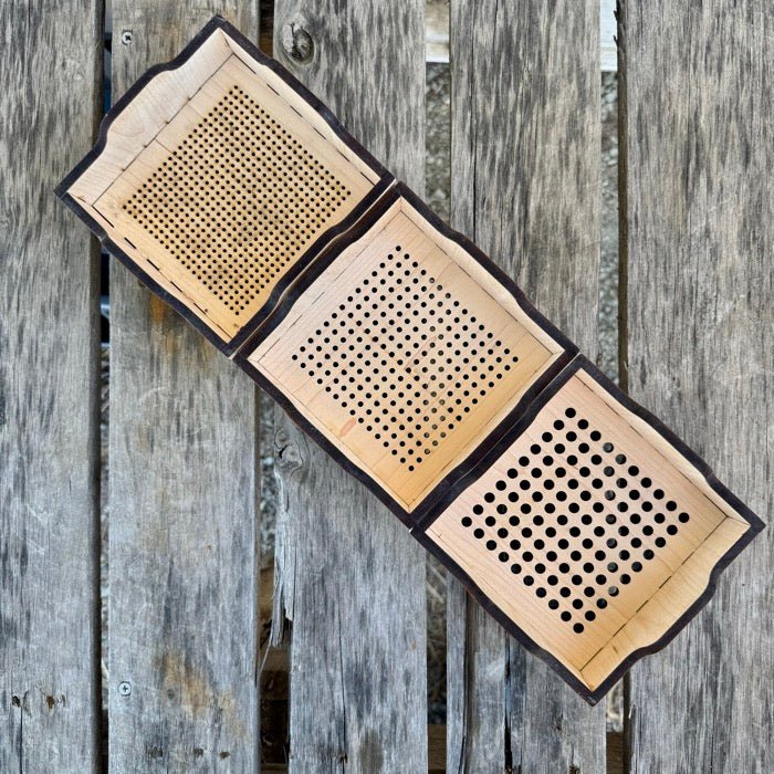 Three wooden coasters with perforated designs on a rustic wooden background