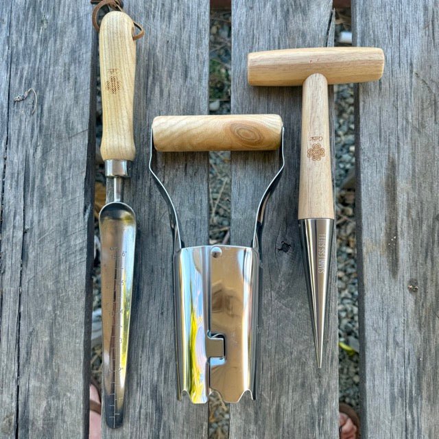 Set of gardening tools with wooden handles on a wooden surface