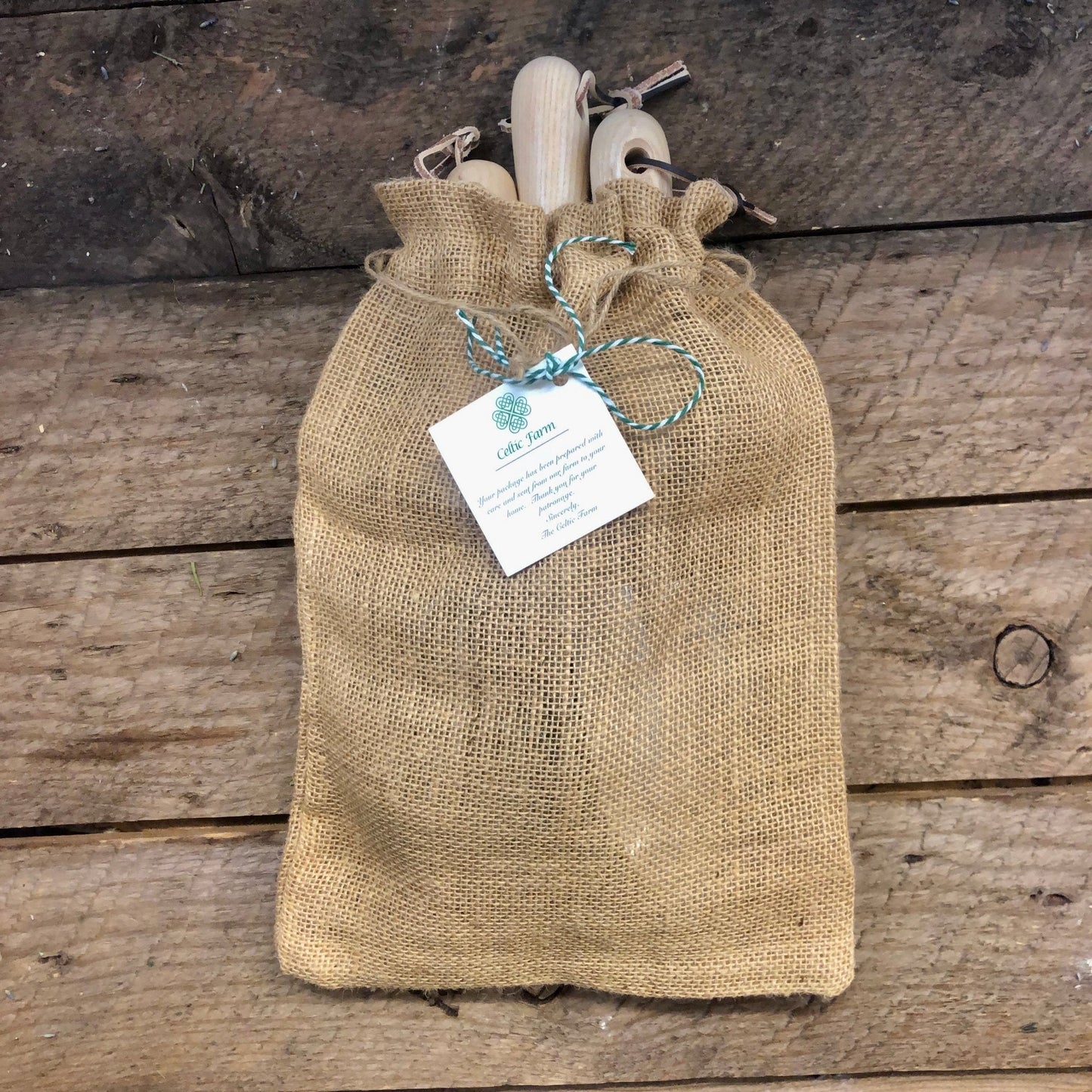 Burlap bag with wooden items and a tag on a wooden surface
