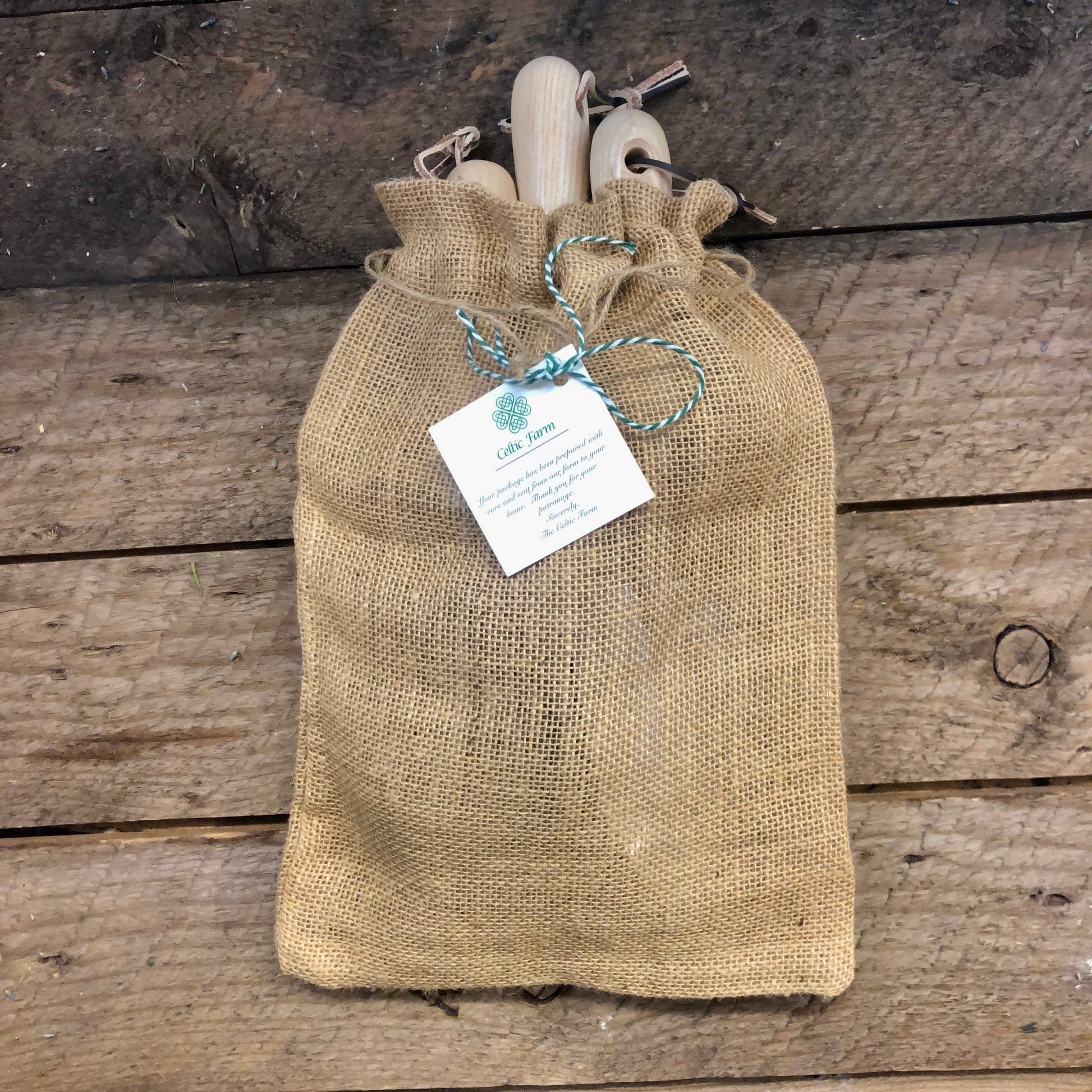 Burlap bag with wooden items and a tag on a wooden surface