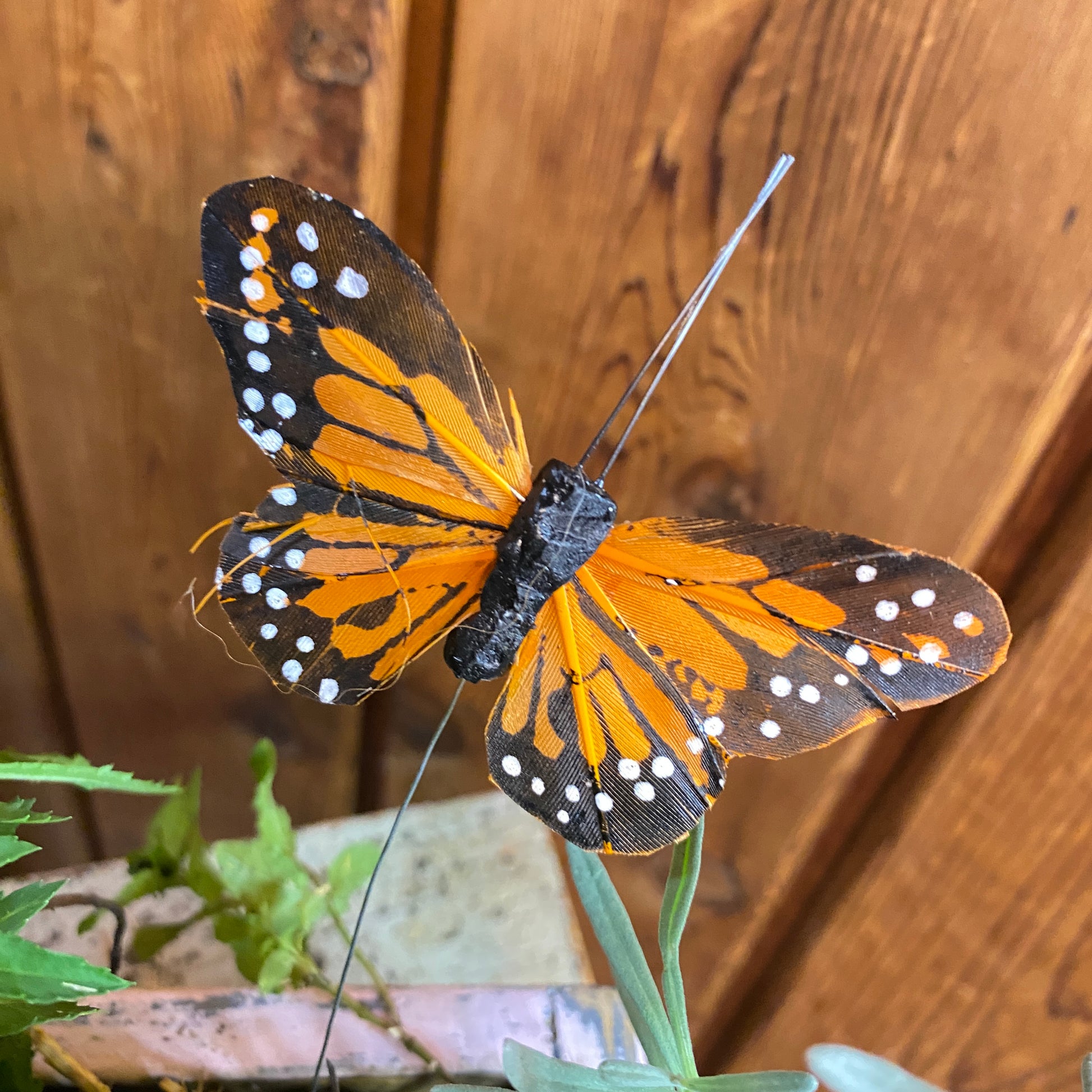 Butterfly-shaped object with orange and black wings on a wooden background